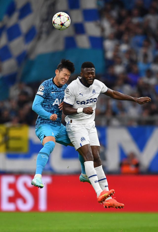 Son Heung-min bumps his face into Chancel Mbemba's shoulder.