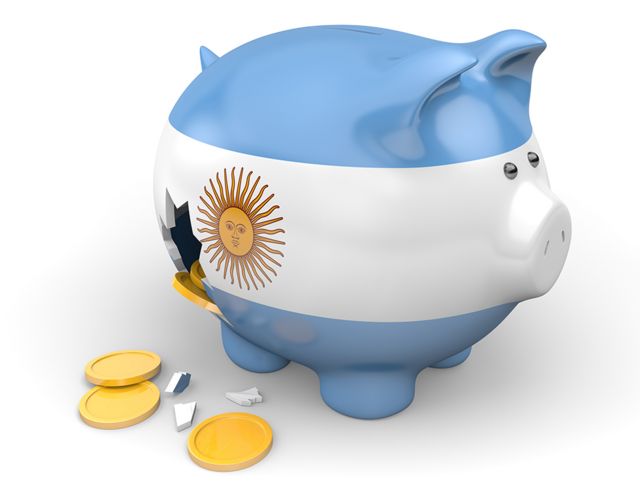 Un chanchito roto con los colores de Argentina y monedas salidas