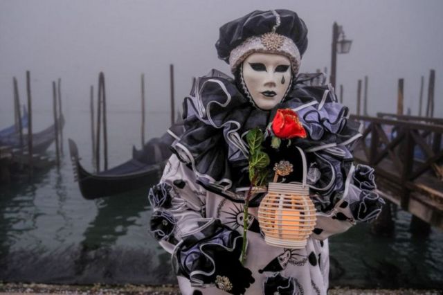 Pessoa fantasiada com máscara no carnaval de Veneza em frente ao canal