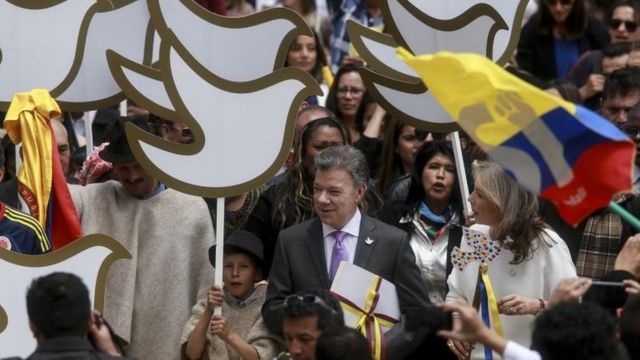 Juan Manuel Santos rodeado de una multitud con pancartas en forma de palomas de la paz.