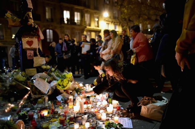 Members of the public view candles and tributes left opposite the main entrance of the Bataclan concert