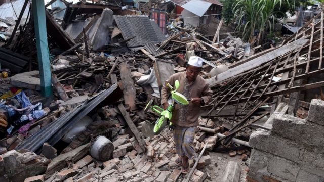 Warga mengangkat sepeda dari reruntuhan rumah yang rusak akibat gempa bumi di Lombok Barat, NTB, Senin (6/8)