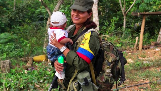 Una mujer guerrillera de las FARC carga un bebé.