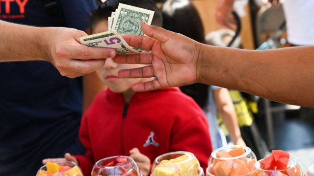 Pessoa paga por frutas em dólares