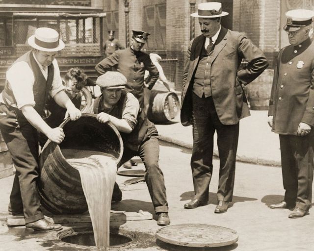 un barril de cerveza ilegal confiscada se vierte por un desagüe