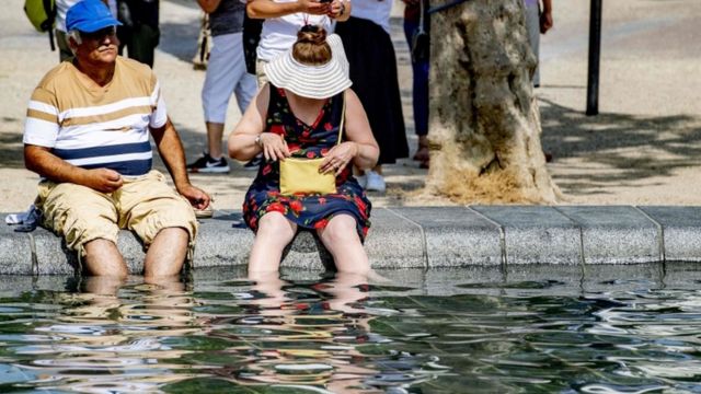 Hombre y mujer refrescándose en una fuente.