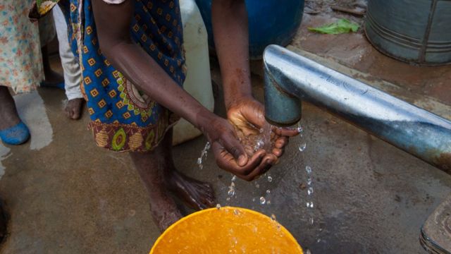 Uma mulher coleta água com as mãos