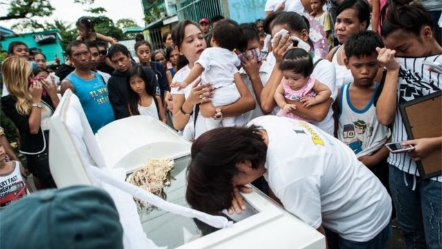 Parentes de uma vítima acusada de ser ladrão e traficante choram sobre o caixão durante um funeral