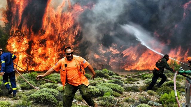 Homens trabalham para apagar o enormes labaredas de fogo na Grécia