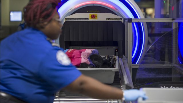 Una agente de seguridad pasa artículos por un escáner 3D en el aeropuerto internacional de Miami en mayo de 2019