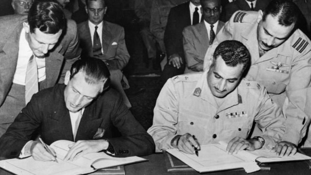 عبد الناصر (على اليمين) وانطوني نونتيغ، وزير الدولة البريطاني للشؤون الخارجية يوقعان يوم 19 أكتوبر/تشرين الأول عام 1954 على اتفاقية جلاء الانجليز. وأجلى آخر جندي بريطاني عن منطقة القناة يوم 18 يونيو/حزيران عام 1956 بعد احتلال استمر 74 عاما.