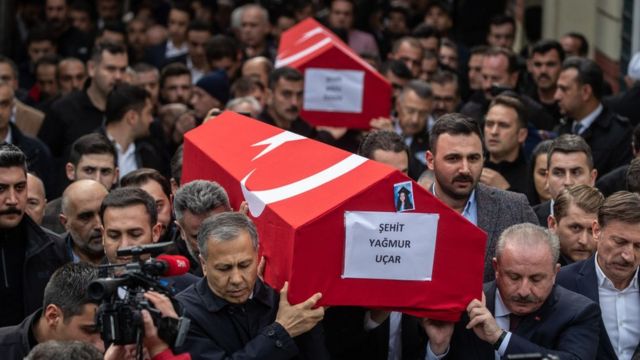 Толпа несет на руках два гроба, покрытых турецкими флагами