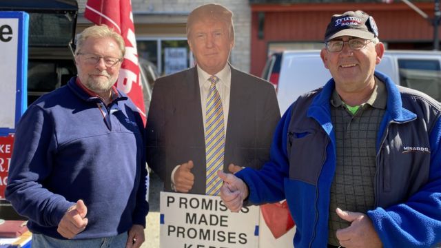 Dois homens em West Bend, no Condado de Washington, com uma placa de Trump