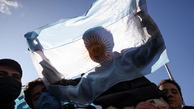 Um menino atrás de uma bandeira da Argentina