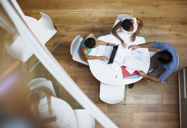 Três pessoas trabalhando em uma mesa