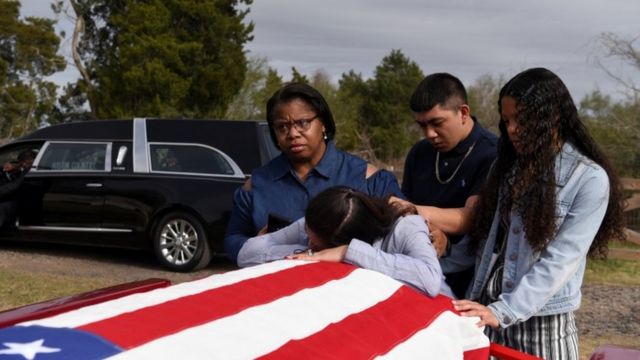 A family says goodbye to their father's flag draped coffin