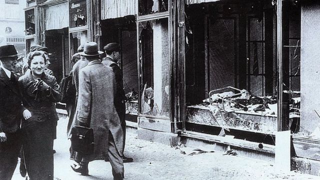 Transeúntes miran las vitrinas destrozadas de las tiendas de judíos en Berlín, tras los ataques de la Noche de los Cristales Rotos (Kristallnacht), noviembre de 1938