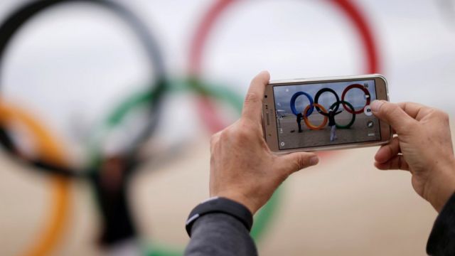 Turista tira foto nos anéis olímpicos instalados na praia de Copacabana