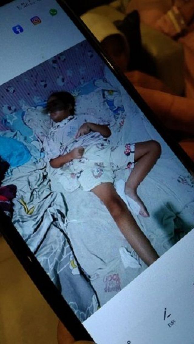 Desi Permatasari menunjukkan foto anaknya Sheena yang terbaring di tempat tidur. 