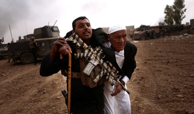 أحد أفراد الفرقة الذهبية يحمل مسنّا إلى مكان آمن لحمايته خلال معركة في منطقة طوبزاوه