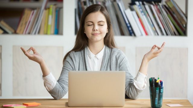Mujer medita frente a la computadora.