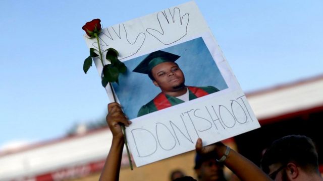 Участник демонстрации держит над головой портрет 18-летнего Майкла Брауна, застреленного в 2014 году в городе Фергюсон, штат Миссури, полицейским