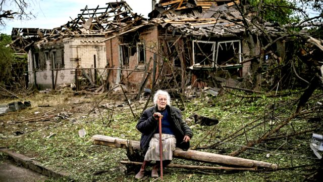 A woman sits in front of two houses that were demolished by a missile attack, which killed another woman, in Druzhkivka, Donetsk