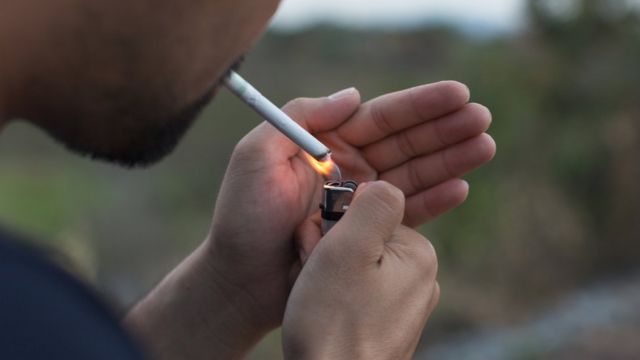 Homem acende cigarro