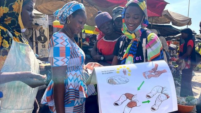 Aisha Mballo (right) shows the women a book that explains the Ponseti method.