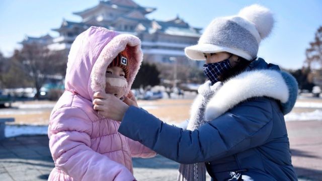 A woman helps her daughter seen wearing a face mask in Pyongyang