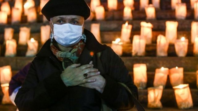 A woman clutches her heart at a candlelit memorial in Brazil
