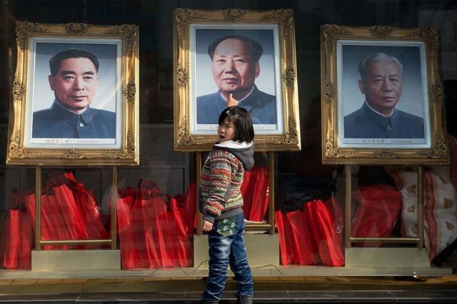 2013年2月26日，一个女孩站在中国前领导人（从左到右）周恩来、毛泽东和刘少奇的画像前。