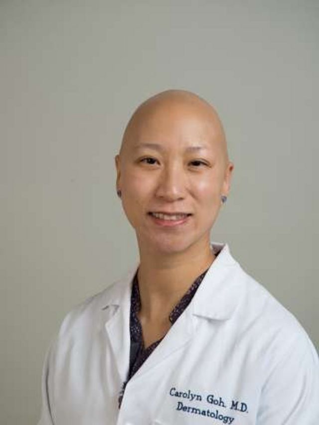 Carolyn Goh smiling for a studio photo;  she is bald