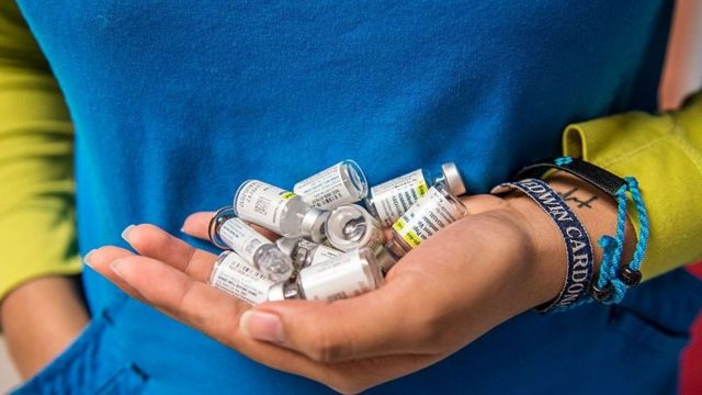 Une infirmière porte des flacons vides de vaccin contre le VPH