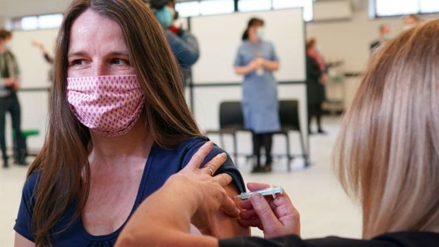 Mulher de máscara sendo vacinada em Penrith, na Inglaterra, em maço