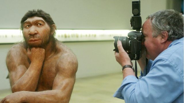 Una figura de neandertal siendo fotografiado.