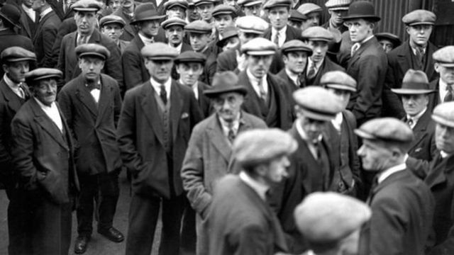 Безробітні чоловіки у черзі на пошук роботи під час Великої депресії 1930-х років