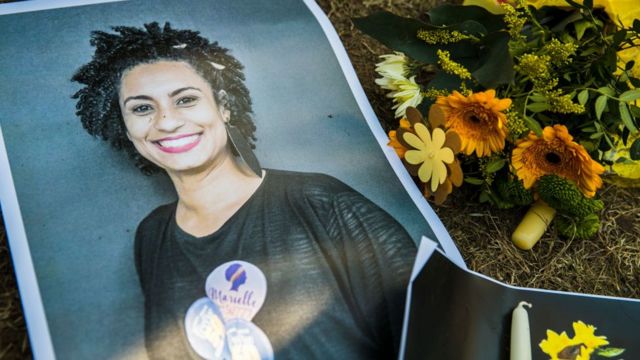 Fotografia de Marielle Franco ao lado de flores em sua homenagem