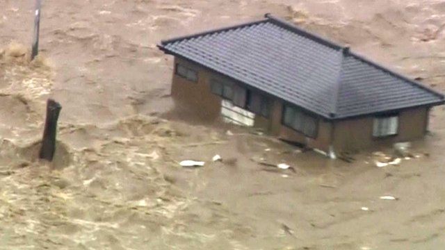 A house is swept down steam by floodwater in Japan