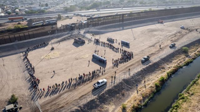 Migrantes en una fila para entrar a EE.UU.