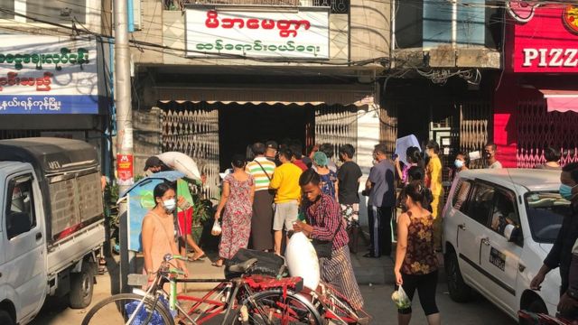 Personas haciendo fila afuera de una tienda de comestibles en Yangon.