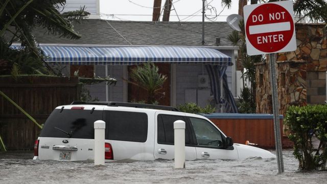 Una camioneta en mitad de una calle inundada.