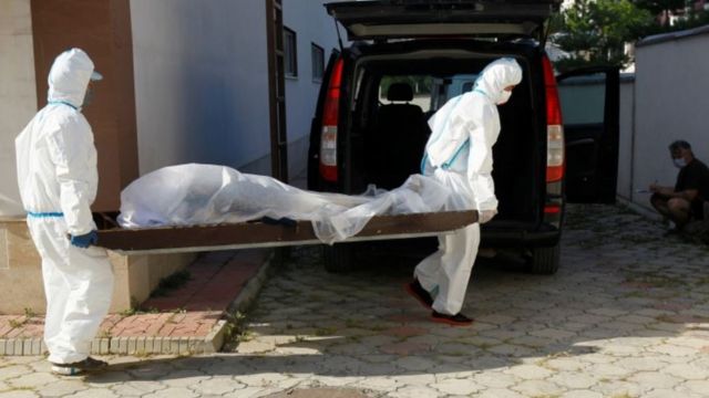 Сотрудники больницы выносят тело одного из умерших