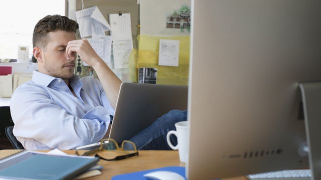 Un hombre estresado frente a dos computadoras