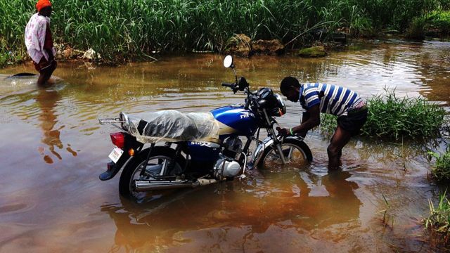 Mwanamume anaosha piki piki yake katika barabara iliyosombwa na maji ya mafuriko katika mji mkuu wa Liberia