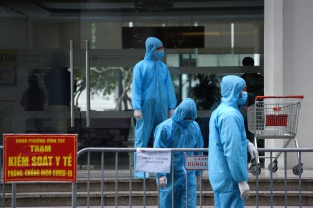 Nhân viên y tế mặc đồ bảo hộ đứng bên ngoài một tòa nhà được cách ly ở Hà Nội, Việt Nam, ngày 29 tháng 1 năm 2021