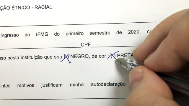 Mão de pele clara marcando a opção "negro" em um formulário de autoidentificação