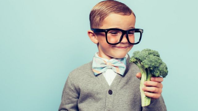 Un niño agarrando un brócoli