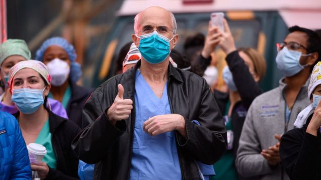 Trabajadores médicos frente al hospital Langone Health de Nueva York mientras la gente aplaude para mostrar su gratitud al personal médico y a los trabajadores esenciales en la primera línea de la pandemia de coronavirus el 19 de abril de 2020 en la ciudad de Nueva York.