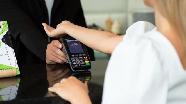 Uma mulher pagando sua refeição em um café usando um chip de pagamento sem contato implantado em sua mão